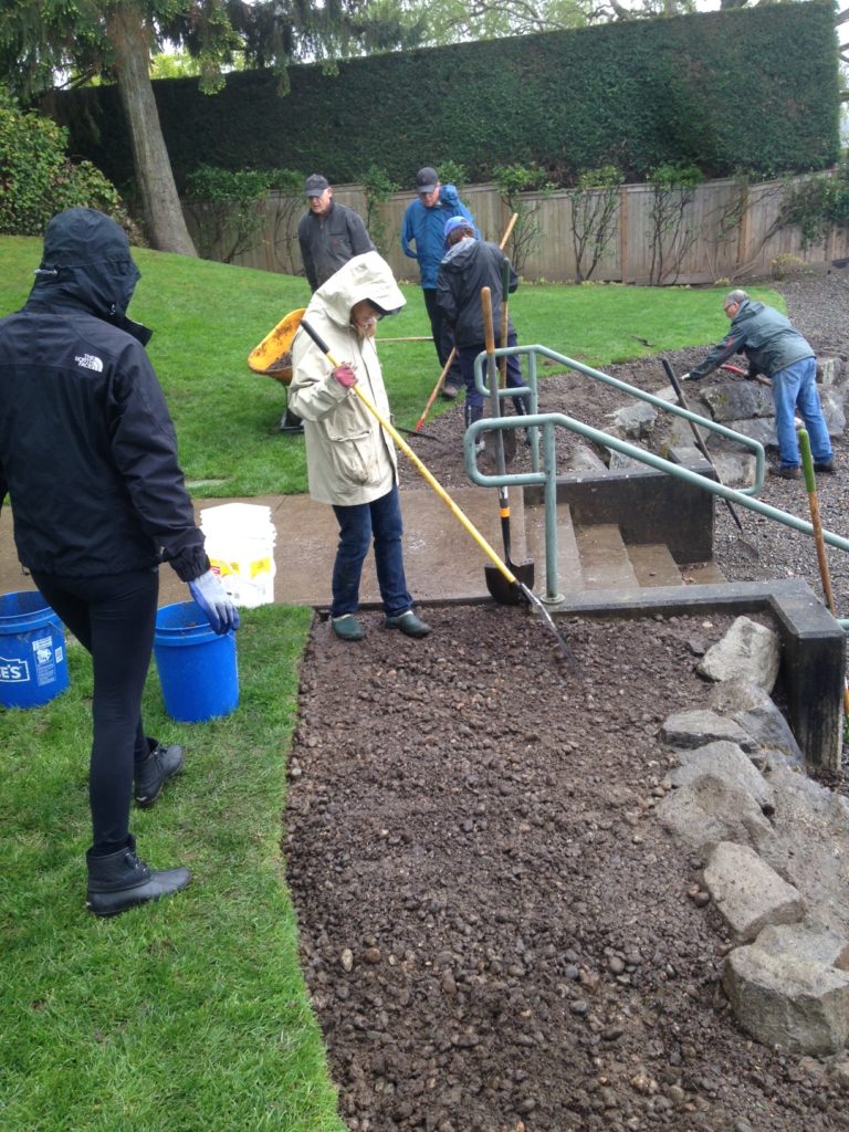 Volunteers leveling gravel path beside outdoor stairs