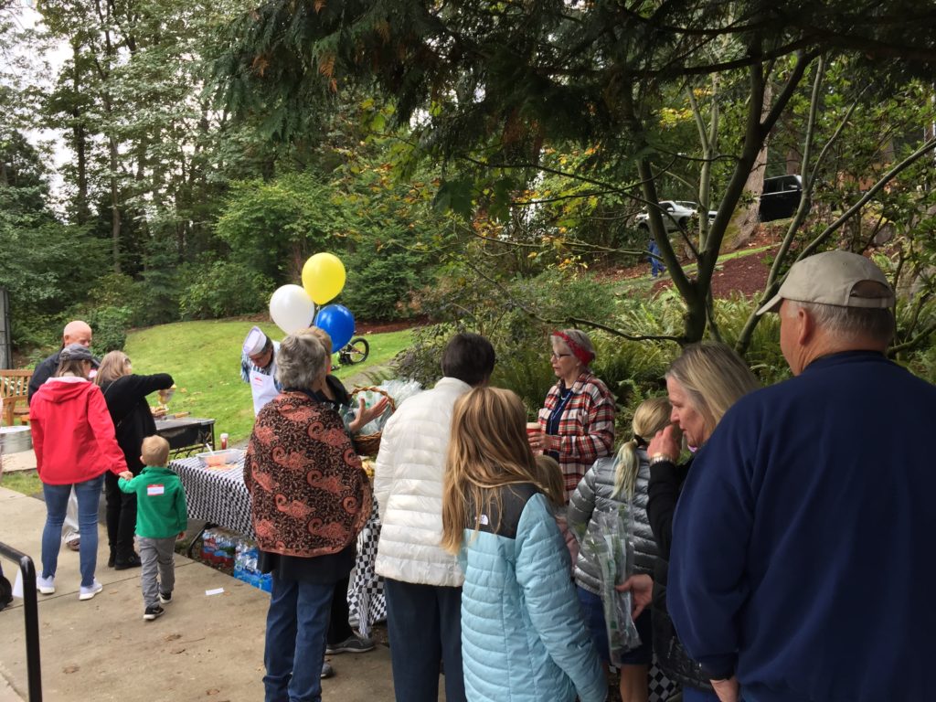 People gathered around outdoor table with balloons