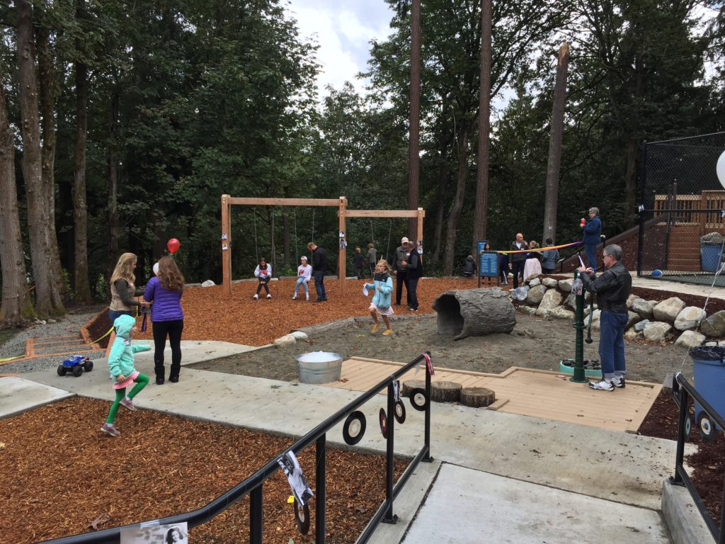 Children playing on swings in wooded playground