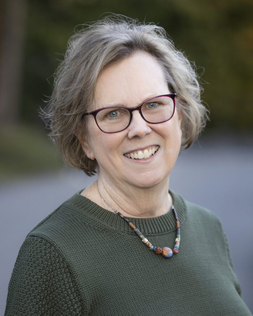 Smiling woman with glasses, short gray hair