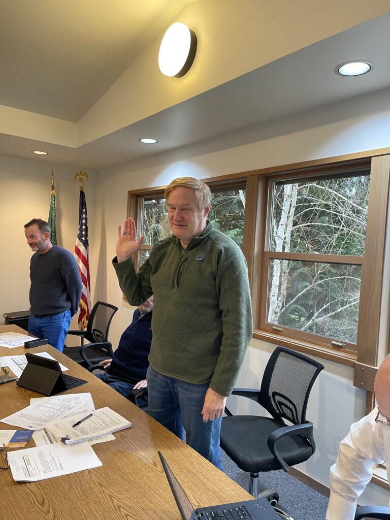 Man standing, raising hand at meeting table