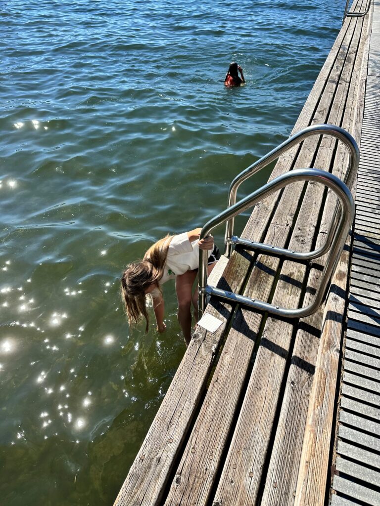 Two swimmers near wooden dock ladder